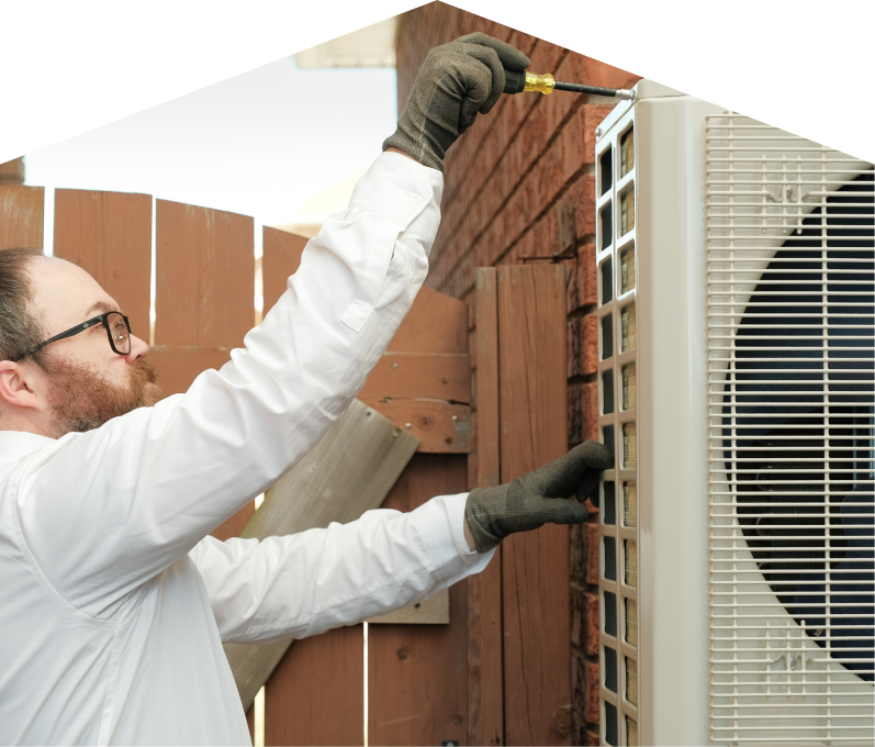 669 Heat service personnel working on an AC condenser, using a screwdriver to secure the unit’s panel outdoors beside a wooden fence. 669 Heat service personnel working on an AC condenser, using a screwdriver to secure the unit's panel outdoors beside a wooden fence.