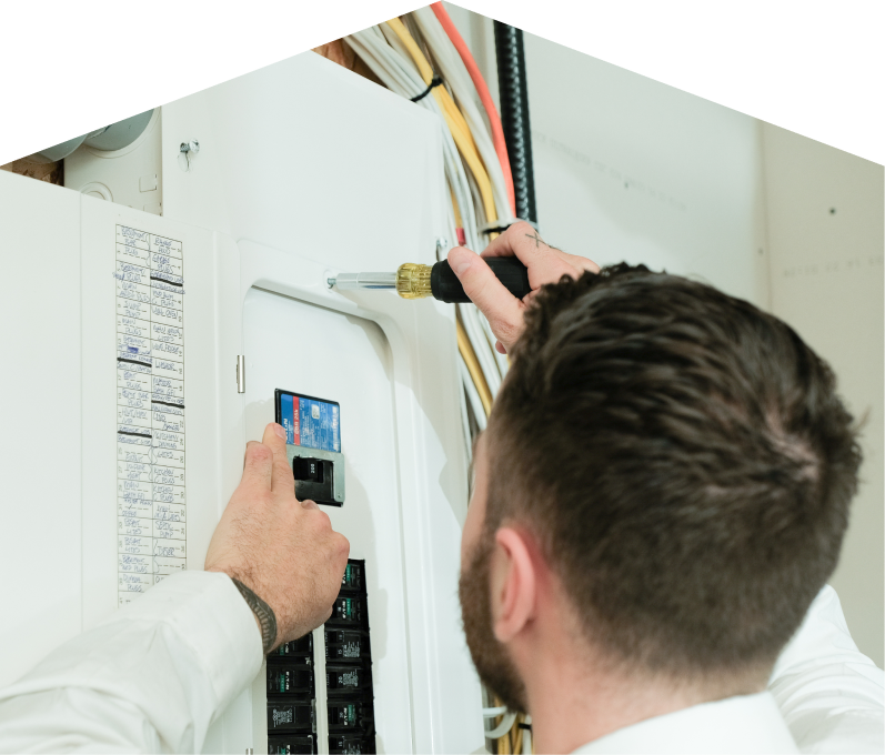 669 Heat electrician using a screwdriver to perform an electrical panel upgrade, working near organized wiring in a residential wall. 669 Heat electrician using a screwdriver to perform an electrical panel upgrade, working near organized wiring in a residential wall.