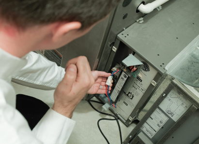 A 669 Heat heating technician inspecting internal wiring during a service check on a residential heating unit. A 669 Heat heating technician inspecting internal wiring during a service check on a residential heating unit.