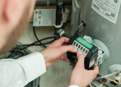A 669 Heat technician adjusts the control module on a residential water heater, verifying proper operating settings. A 669 Heat technician adjusts the control module on a residential water heater, verifying proper operating settings.