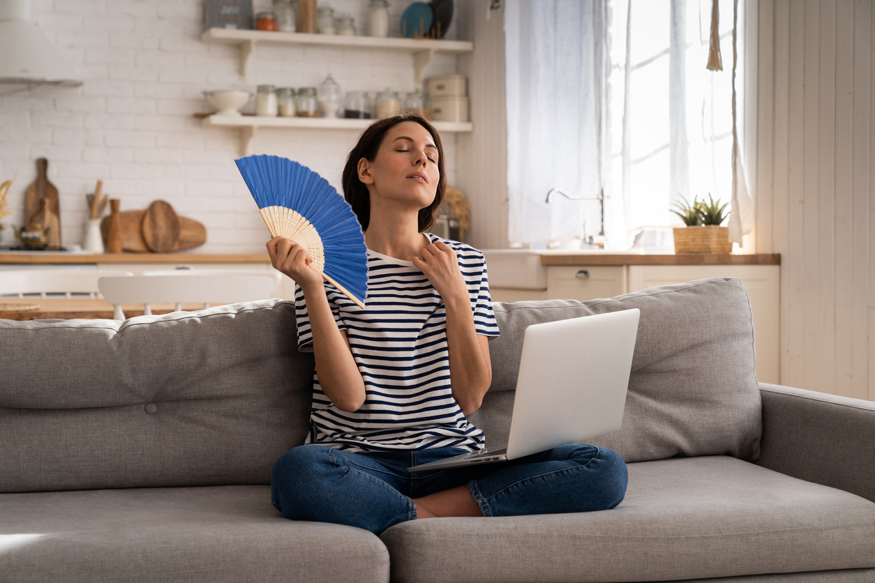 Young woman suffers from heatstroke flat without air-conditioner waving fan sitting on couch at home Young woman suffers from heatstroke flat without air-conditioner waving fan sitting on couch at home